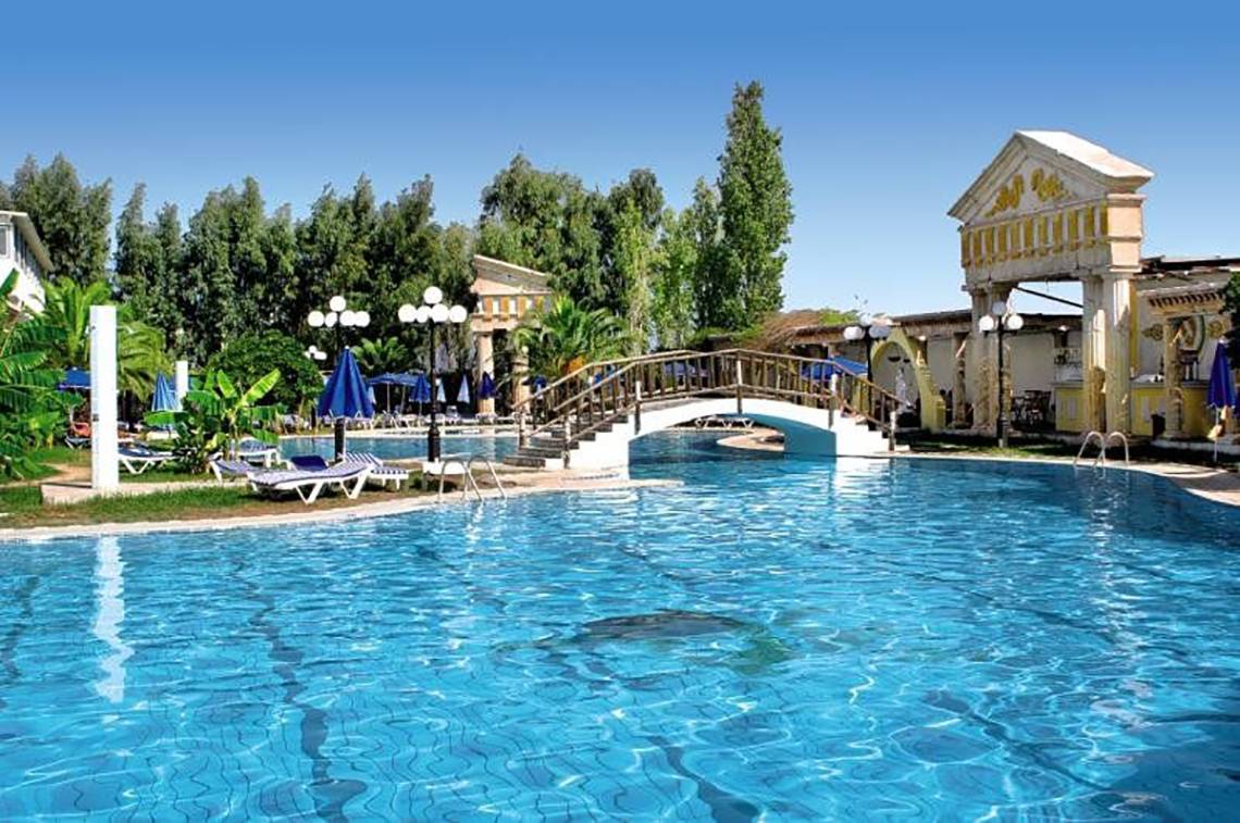 Außenpool des Smy Kos Beach & Splash Hotels mit Brücke und Sonnenliegen.