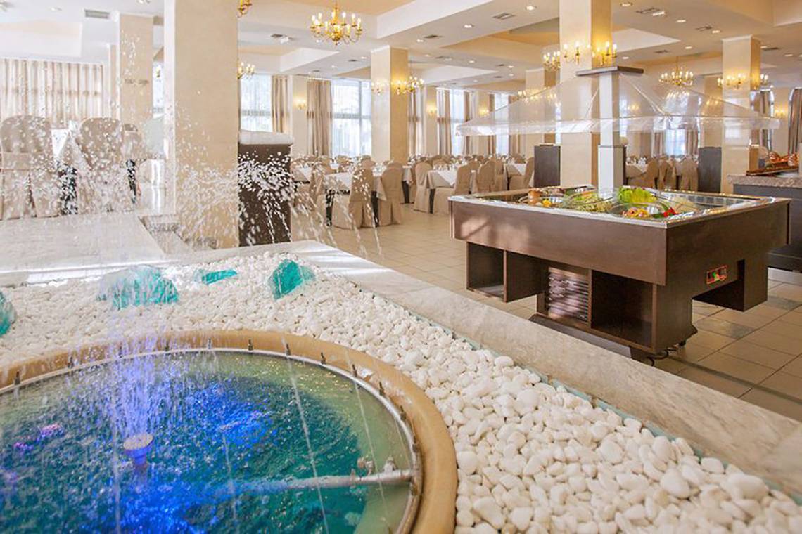 Innenbereich des Smy Kos Beach & Splash Hotels mit einem Restaurantbereich, Wasserbrunnen und Speisen.