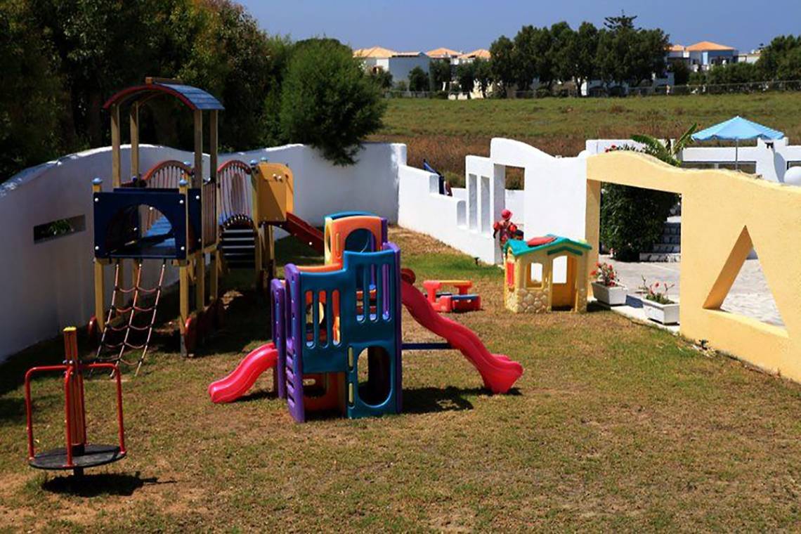 Kinderspielplatz im Freien beim Smy Kos Beach & Splash Hotel mit bunten Spielgeräten und einer Rasenfläche.