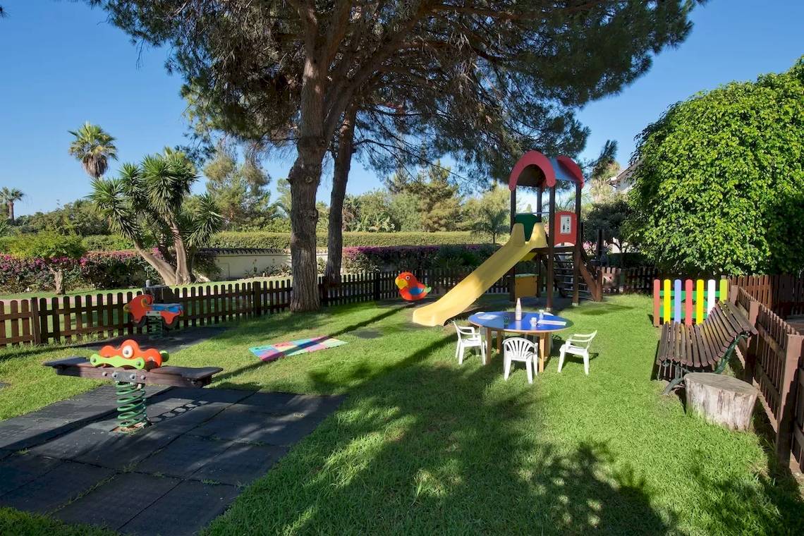 Kinderspielplatz im Bluebay Banus Hotel mit Rutsche, Tisch und Stühlen.