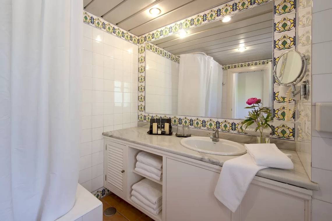 Badezimmer im Bluebay Banus Hotel mit weißem Waschbecken und gefalteten Handtüchern.