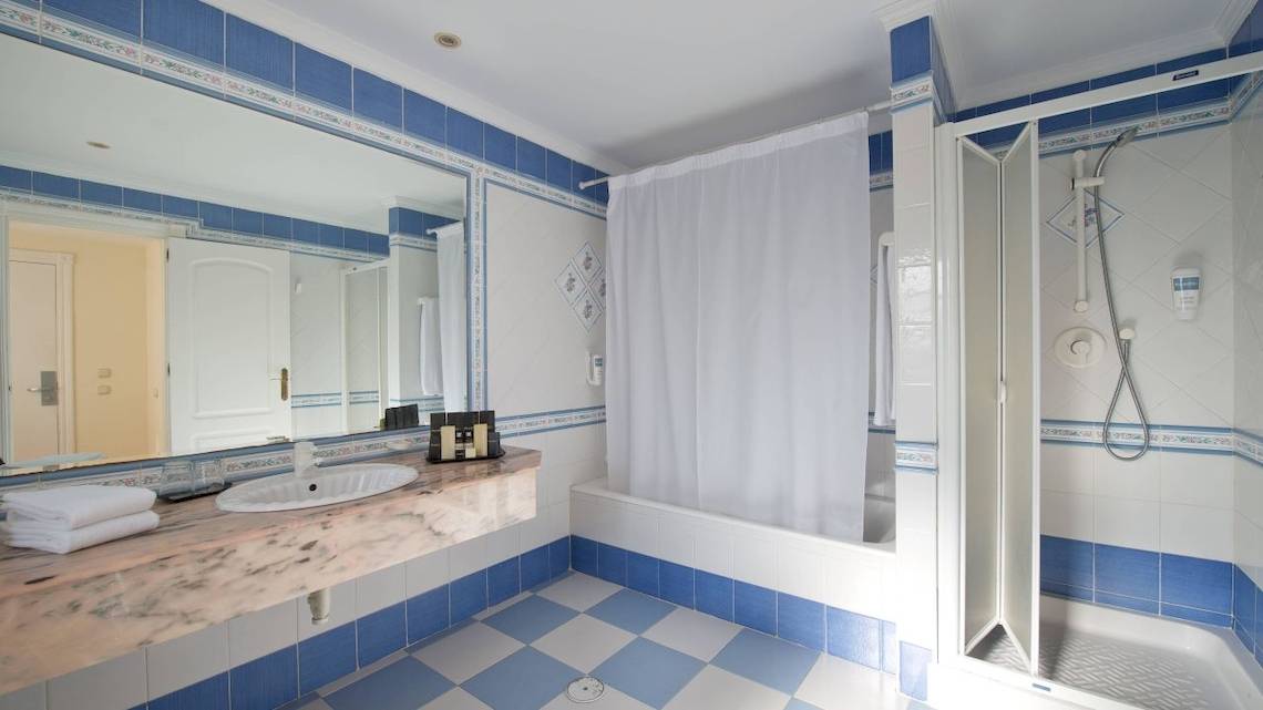 Badezimmer im Bluebay Banus Hotel mit blauen Fliesen und Marmorarbeitsplatte.