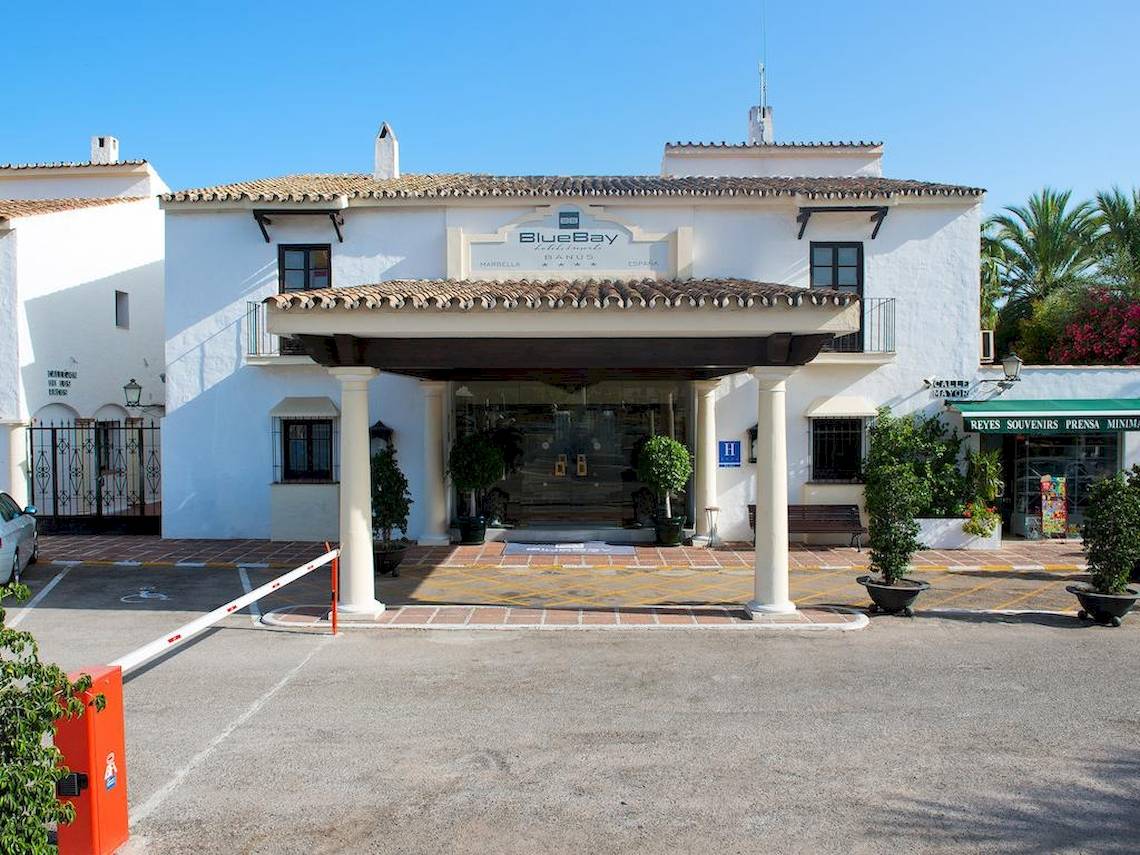 Eingangsbereich des Bluebay Banus Hotels mit weißen Säulen und einer gefliesten Eingangsfläche.