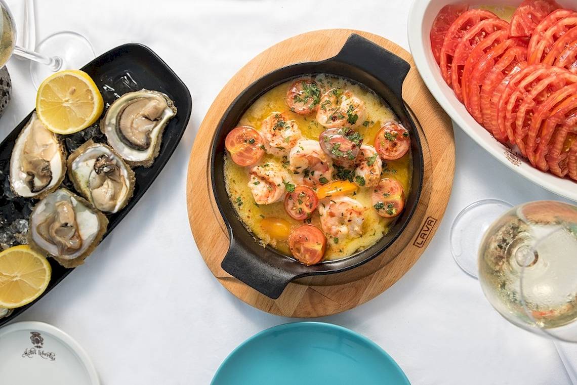 Essen serviert auf dem Tisch im Rixos Premium Dubrovnik, einschließlich einer Schüssel Garnelen mit Tomaten und Sauce, Austern und Salat.