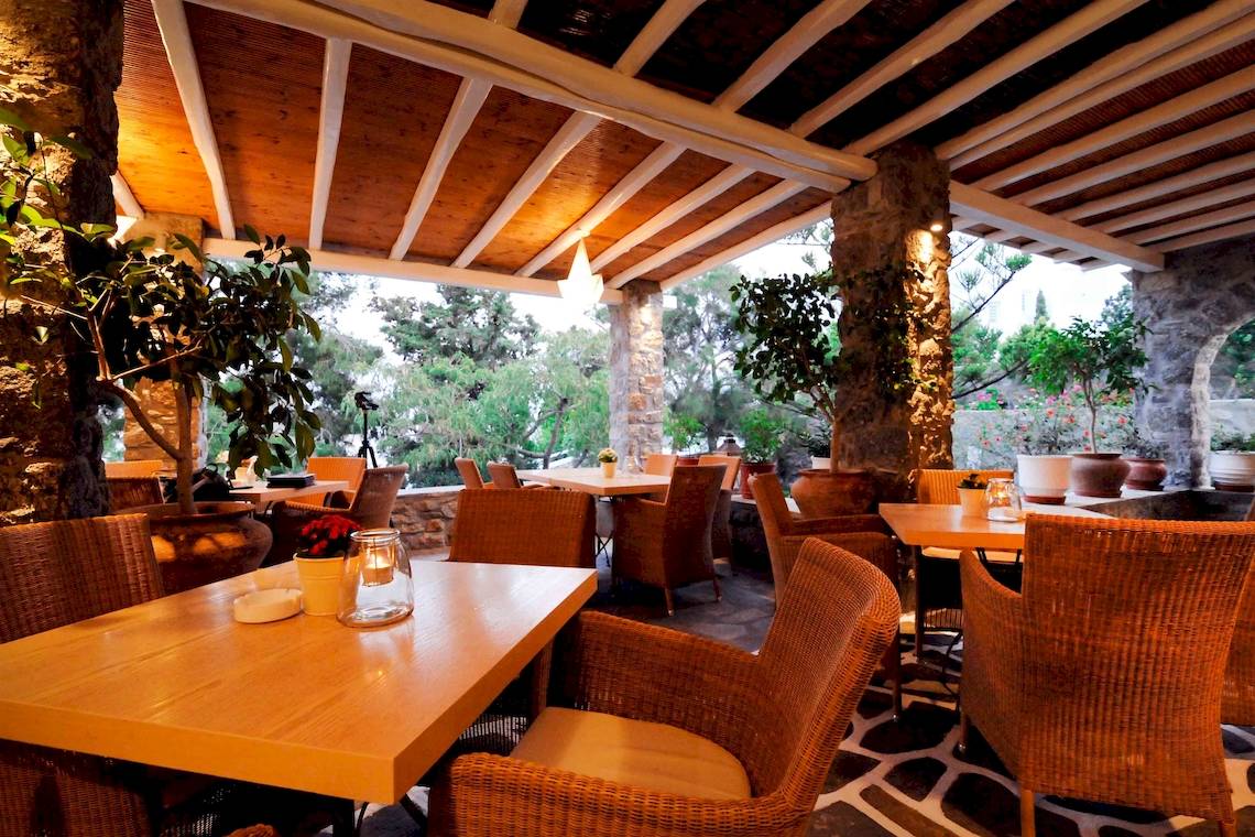 Foto der Terrasse des Kamari Hotels mit Tischen, Stühlen und Pflanzen.