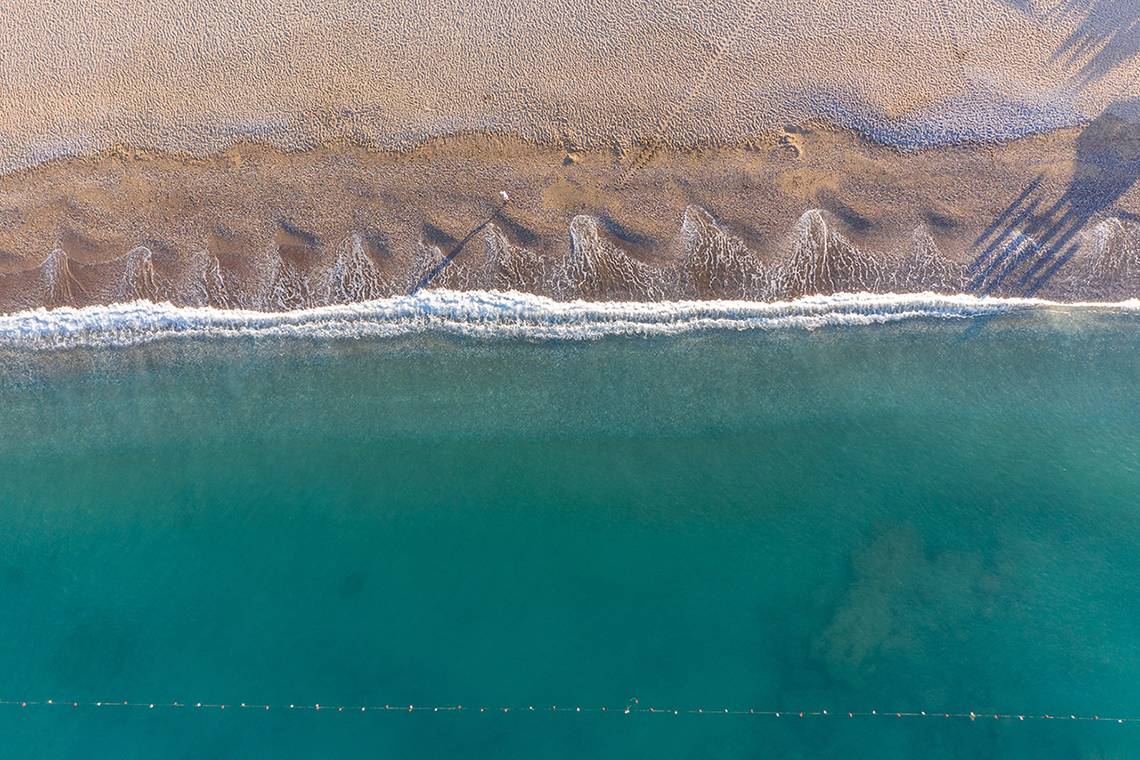 Oberflächenansicht eines Strandes mit türkisfarbenem Meer und Sonnenschirm