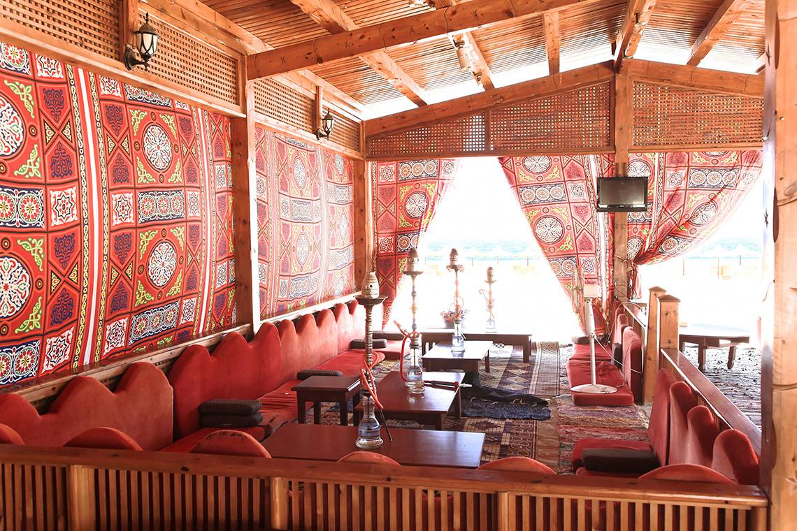Innenansicht der Lounge im Three Corners Happy Life Beach Resort mit roten Sofas und orientalischen Wandbehängen.