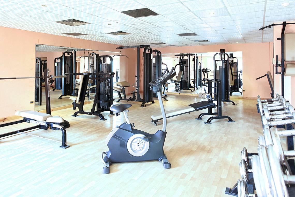 Fitnessstudio im Three Corners Happy Life Beach Resort mit verschiedenen Geräten und Trainingsbereichen.