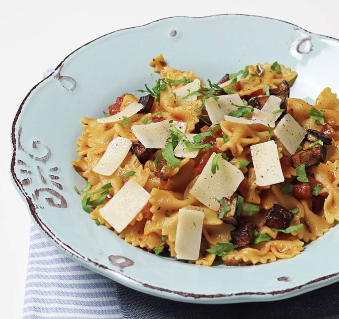 Nahaufnahme von Pasta mit Pilzen und Tomaten auf einem blauen Teller