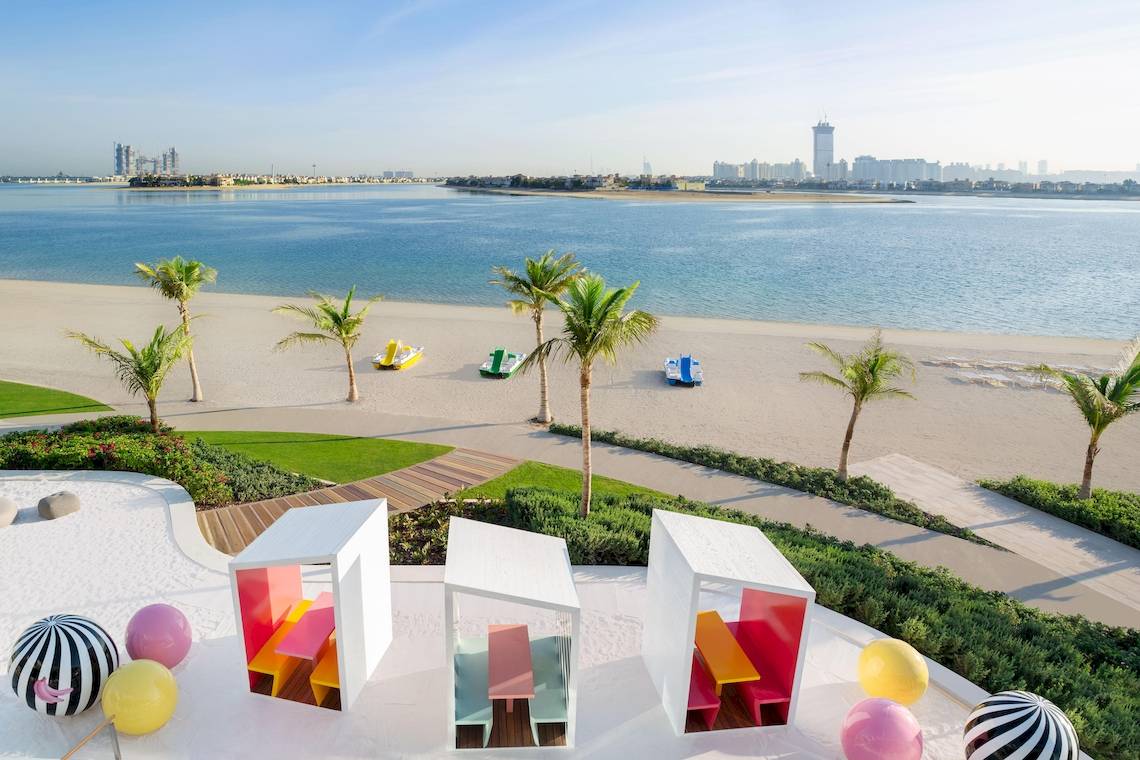 Aussicht auf den Strand des W Dubai - The Palm mit bunten Pavillons und Palmen