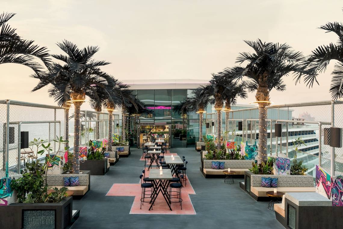 Dachterrasse des W Dubai - The Palm mit bunten Sitzbereichen und Palmen