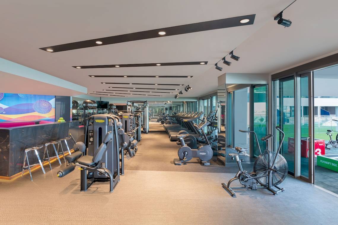 Innenansicht des Fitnessstudios im W Dubai - The Palm mit verschiedenen Trainingsgeräten und einer offenen Glastür.