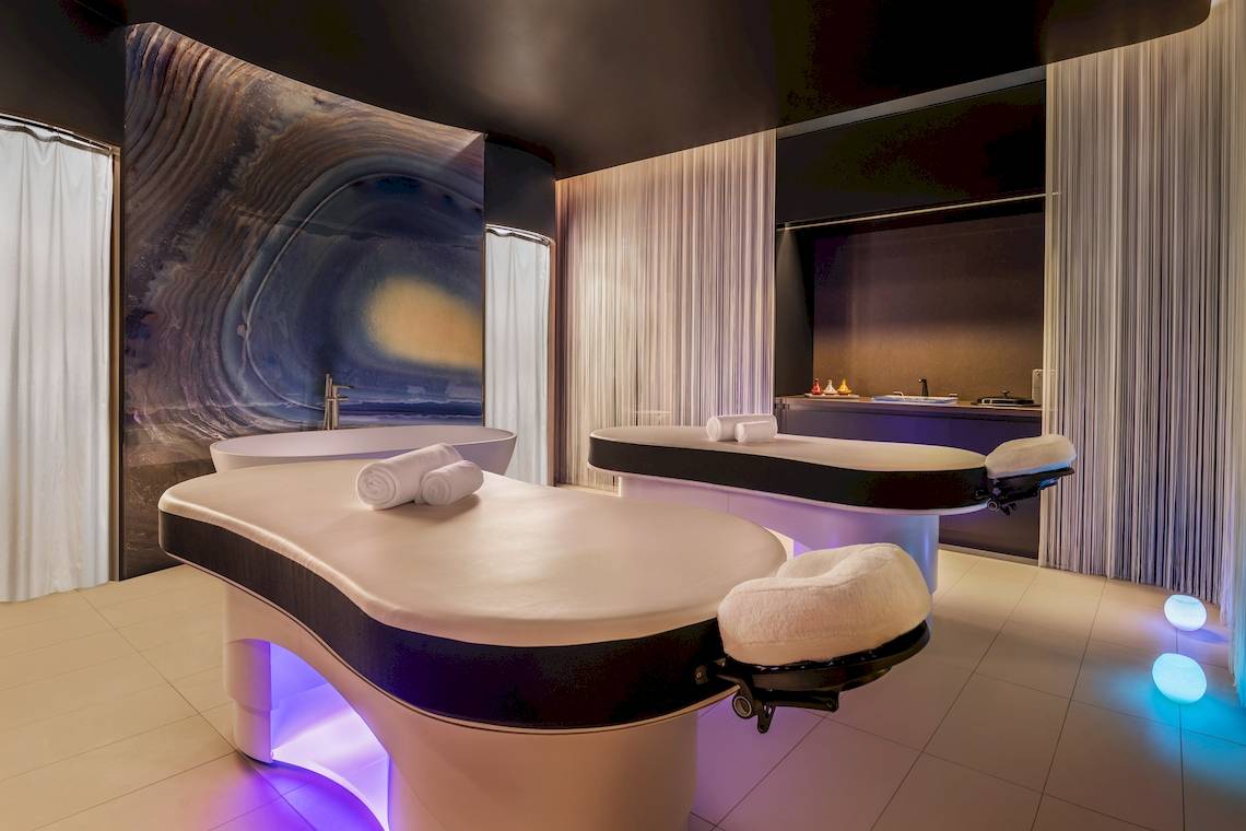Behandlungsraum im W Dubai - The Palm mit zwei Massagetischen und Kunstwerk an der Wand.