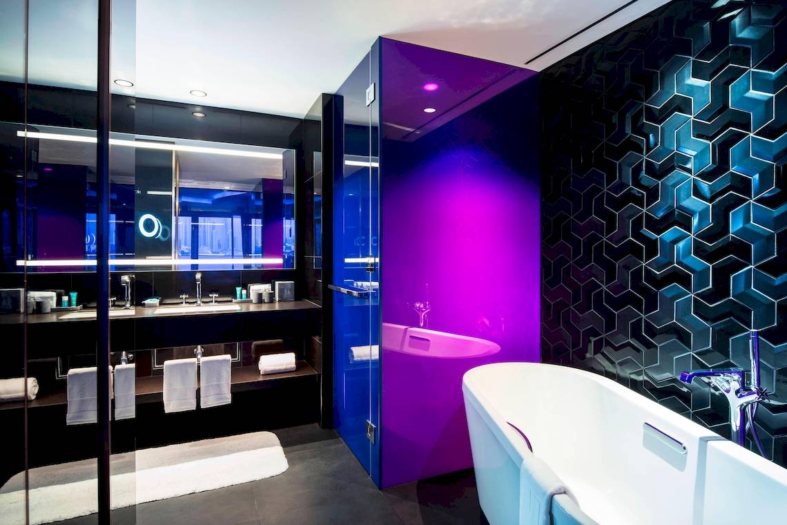 Badezimmer im W Dubai - The Palm Hotel mit violetter Wand und Badewanne.