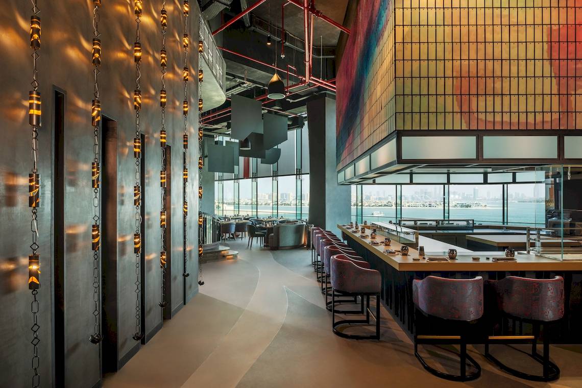 Innenansicht des Restaurants im W Dubai - The Palm mit farbenfrohen Wänden und Blick auf das Meer.