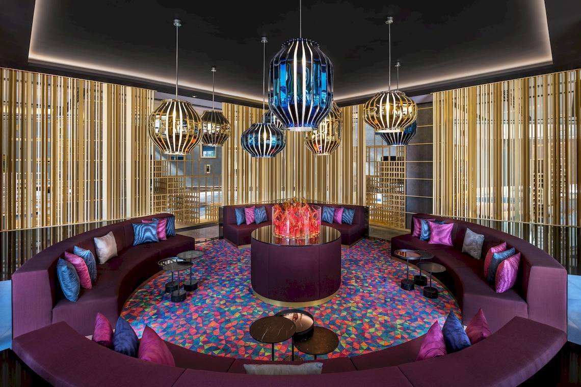 Lobby-Lounge-Bereich des W Dubai - The Palm mit runden Sofas und farbigem Bodenmuster.