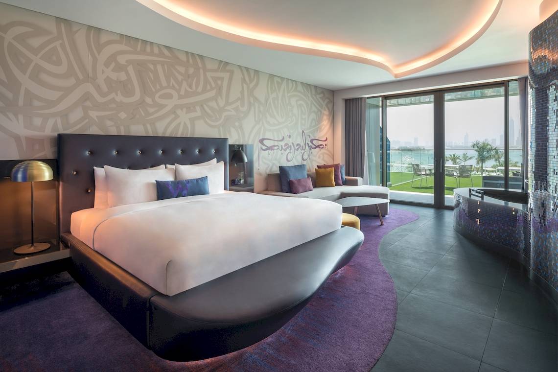 Schlafzimmer im W Dubai - The Palm Hotel mit einem großen Bett, Kunst an der Wand und einer Terrasse.