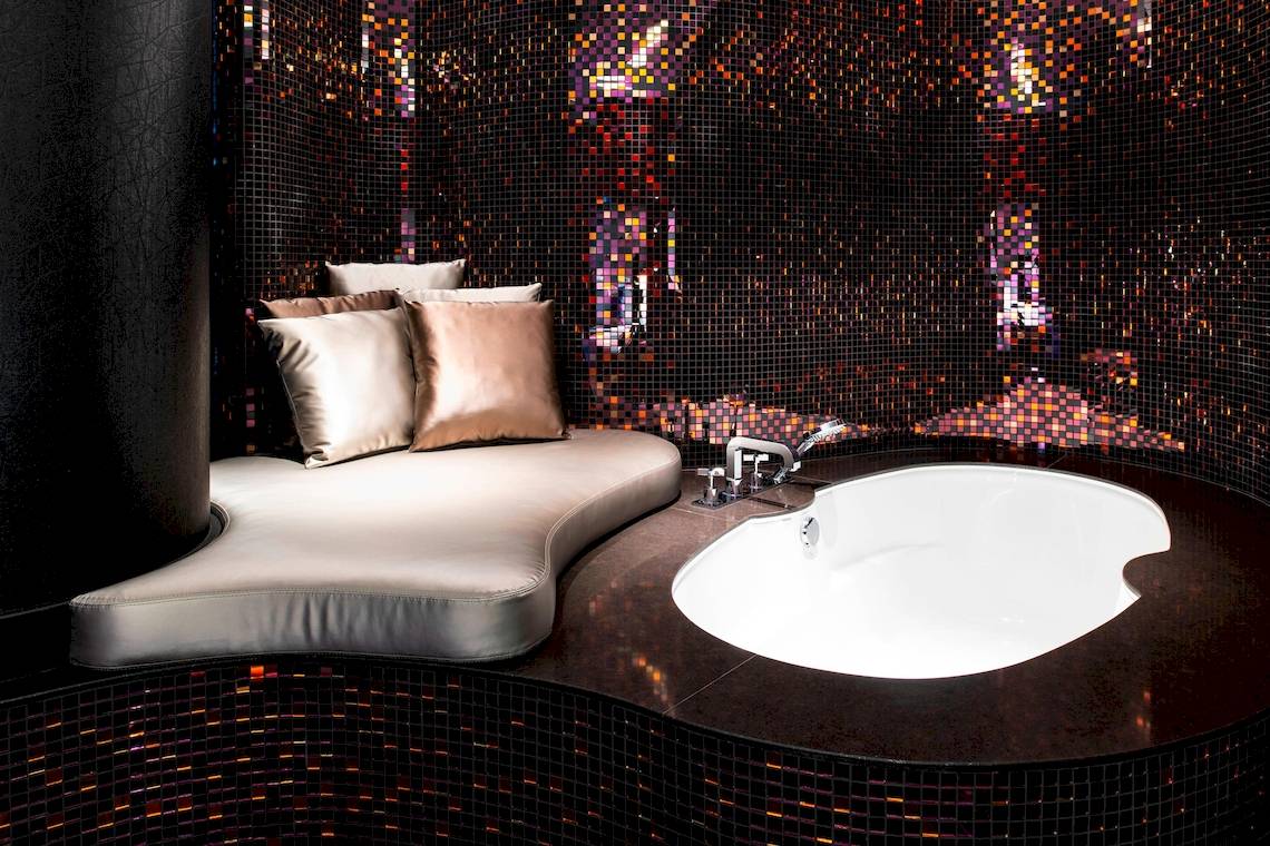 Badezimmer im W Dubai - The Palm mit geschwungener Bank, Kissen und Badewanne.