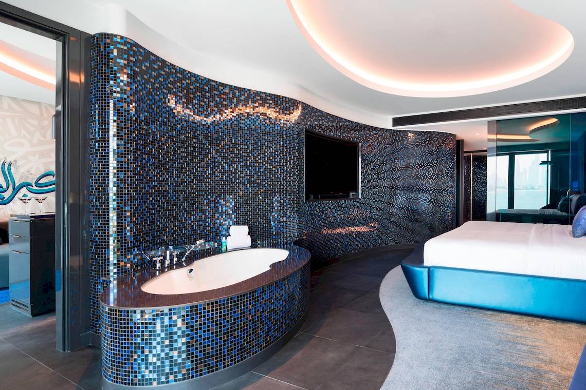 Das Badezimmer der Suite im W Dubai - The Palm mit blauen Fliesen und einer Badewanne.