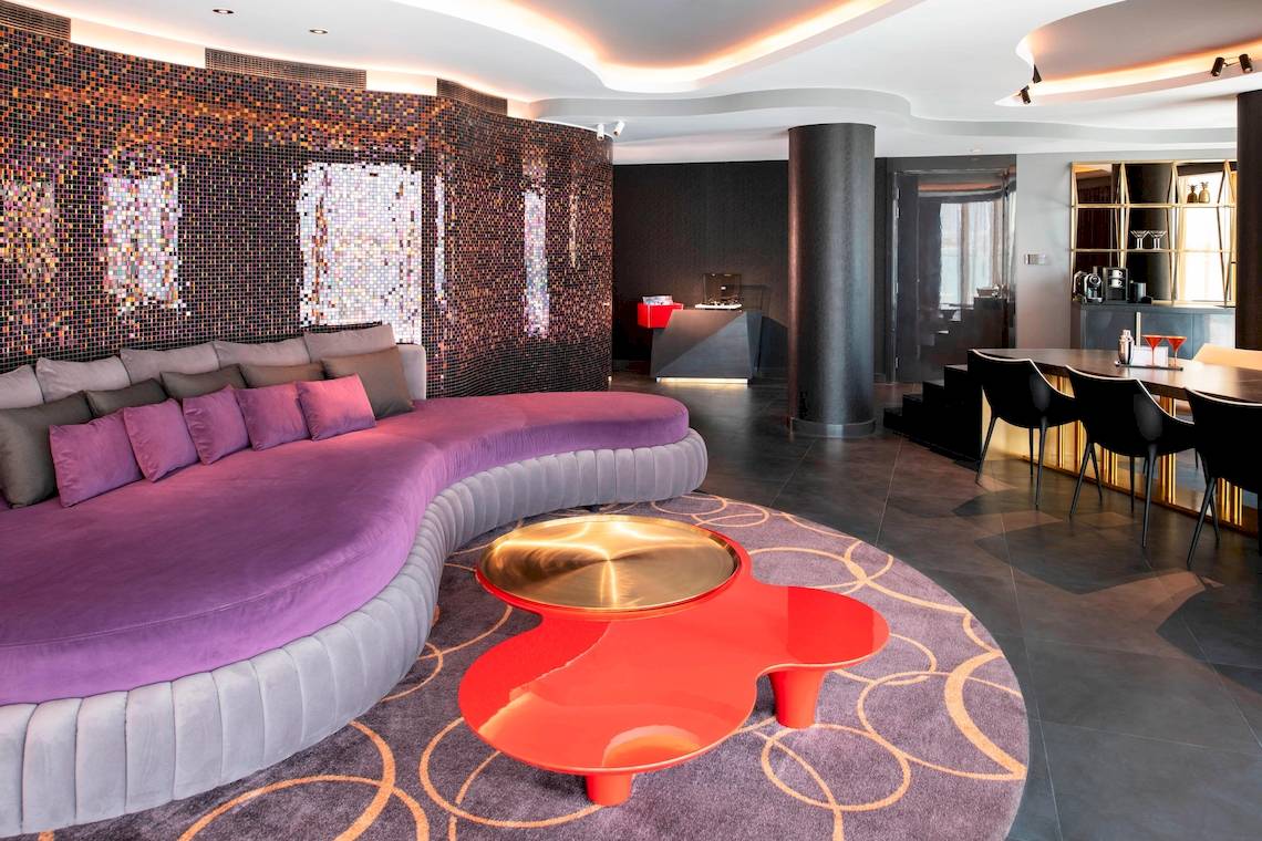Lobby-Lounge-Bereich des W Dubai - The Palm Hotels mit einer violetten Couch und einem roten Tisch.