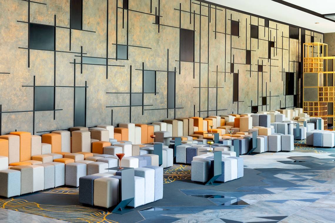 Loungebereich im W Dubai - The Palm mit modularen Sofas und geometrischem Wanddesign.