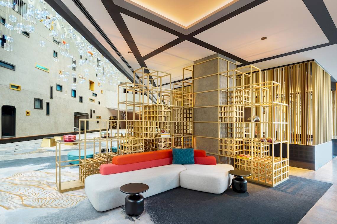 Lobby des W Dubai - The Palm Hotels mit modernen Möbeln und goldenen Strukturen.