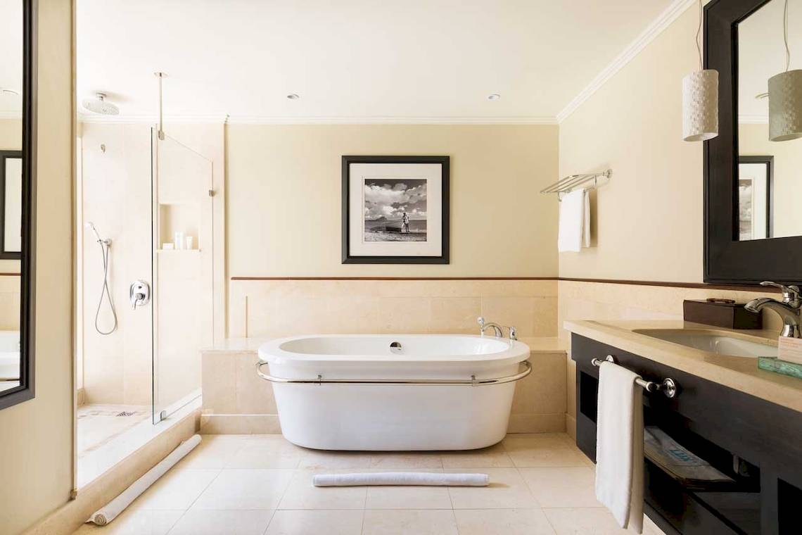 Badezimmer im LUX Le Morne mit Badewanne, Dusche und Waschbecken.