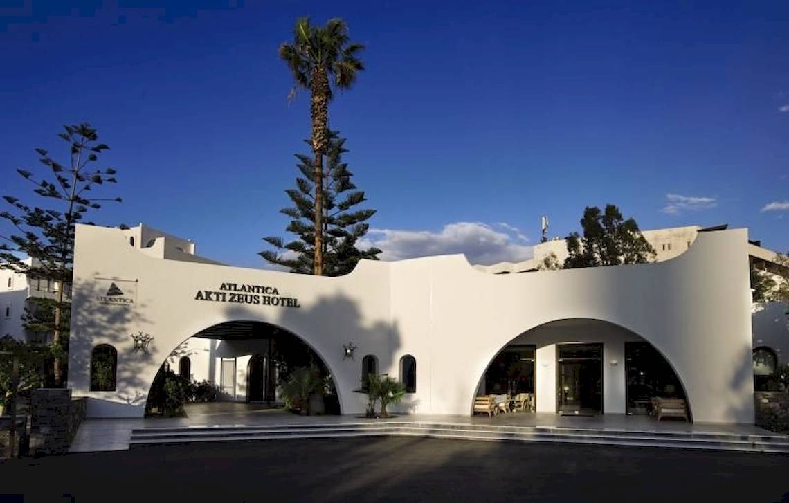 Vorderansicht des Atlantica Akti Zeus Hotels mit zwei bogenförmigen Eingängen und Palmen im Hintergrund.