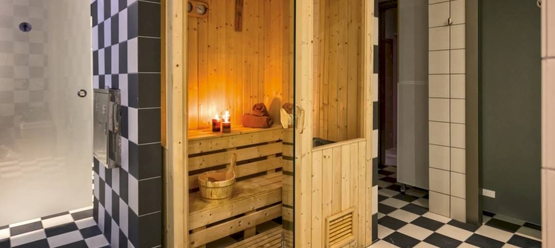 Sauna im Lagomandra Beach Hotel mit Holzwänden, Kerzen und einem Eimer.