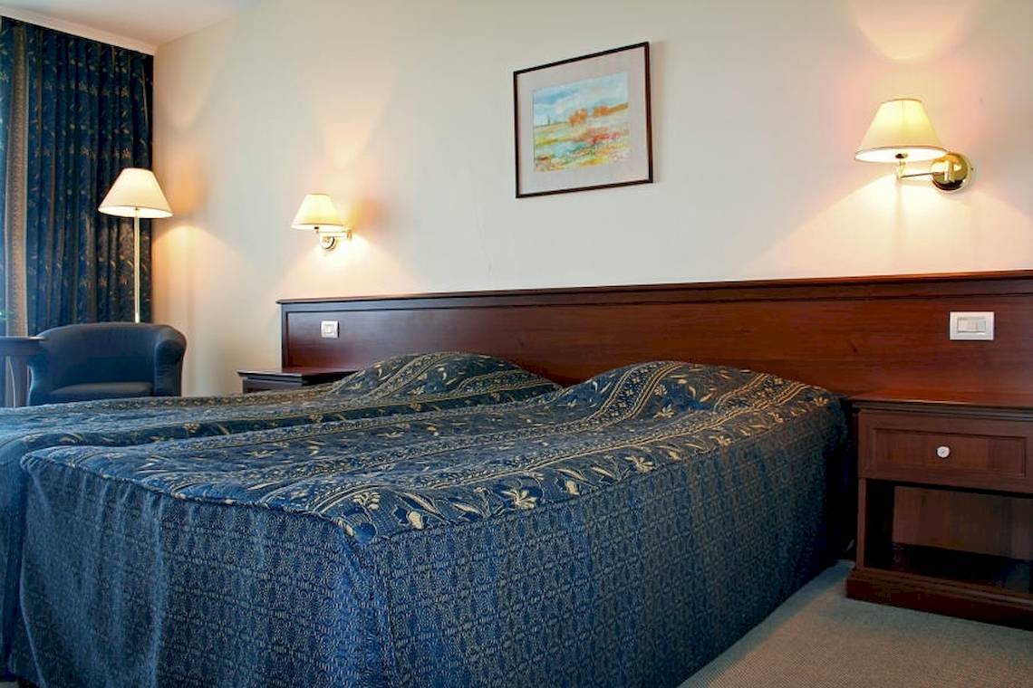 Doppelbettzimmer im Riviera Beach Hotel mit blauen Bettdecken und Nachttischen.