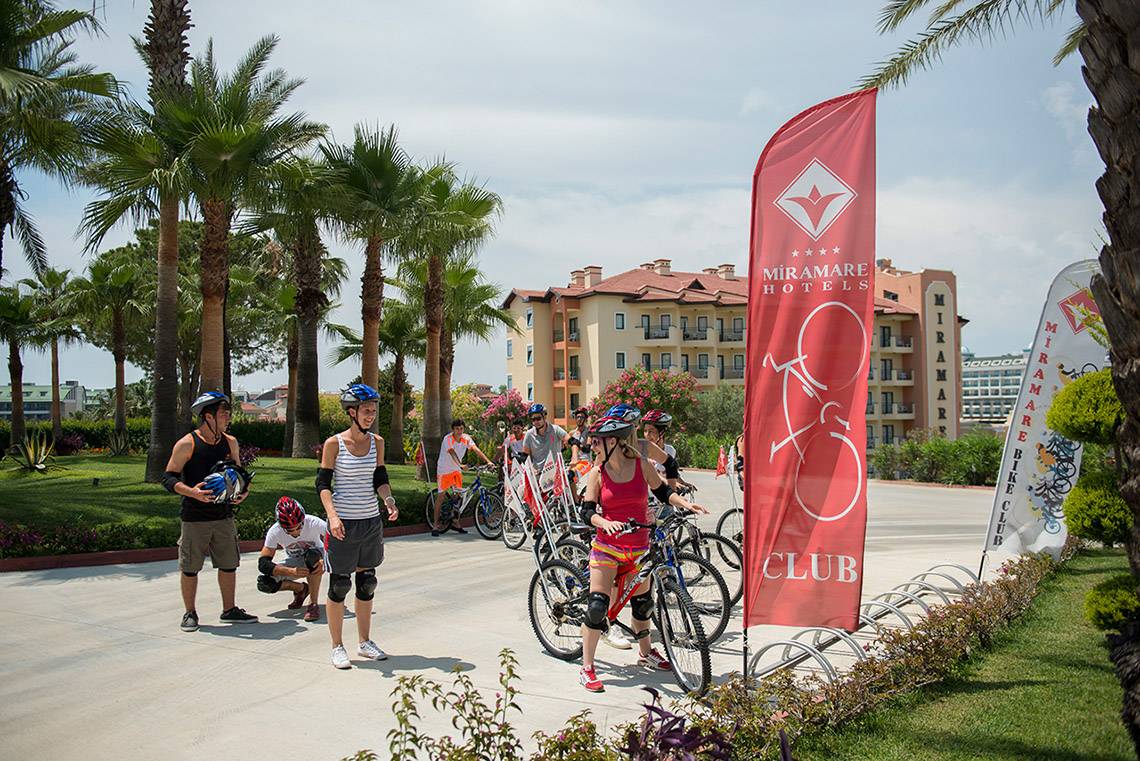 Gruppe von Radfahrern vor dem Miramare Hotel, einige bereiten sich auf eine Fahrradtour vor.