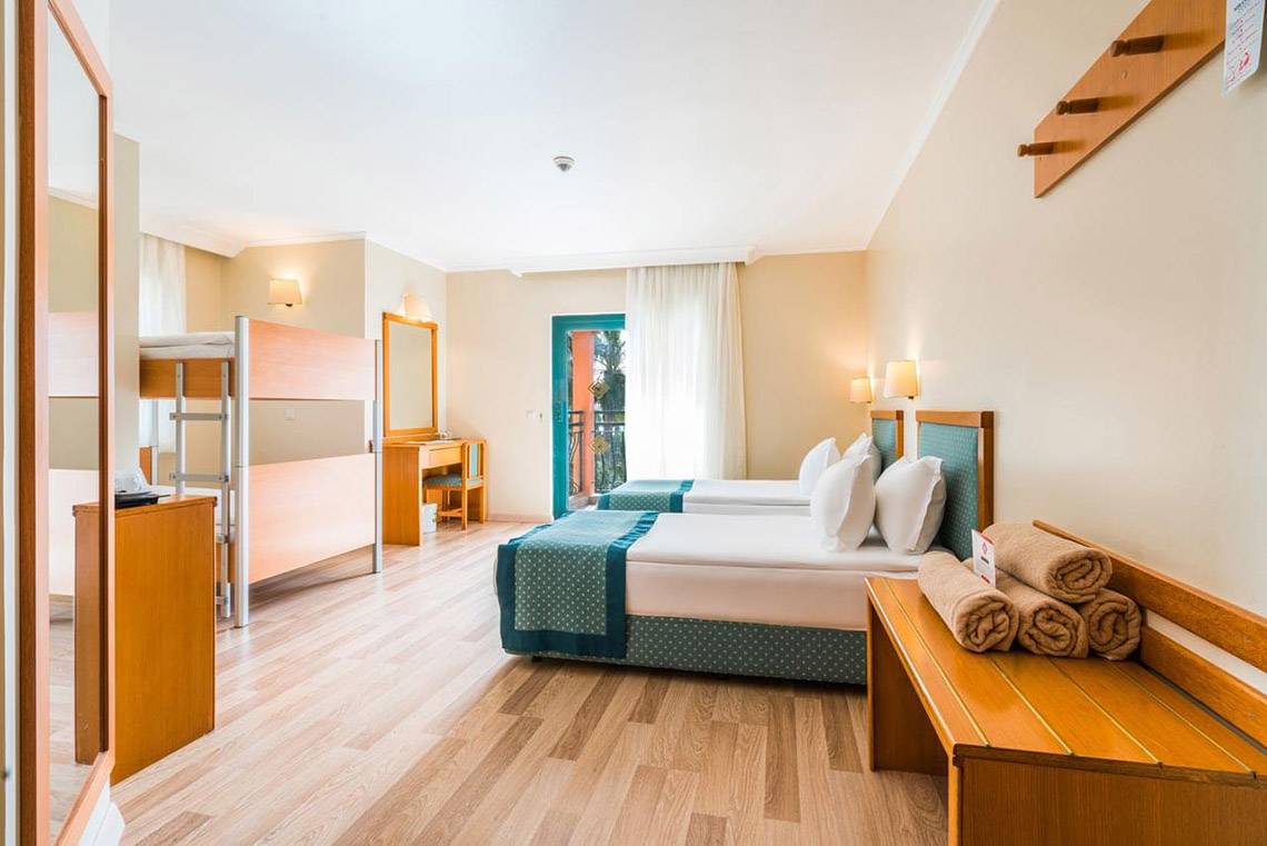 Innenansicht des Miramare Queen Hotels mit zwei Betten, Schreibtisch und Balkontür.