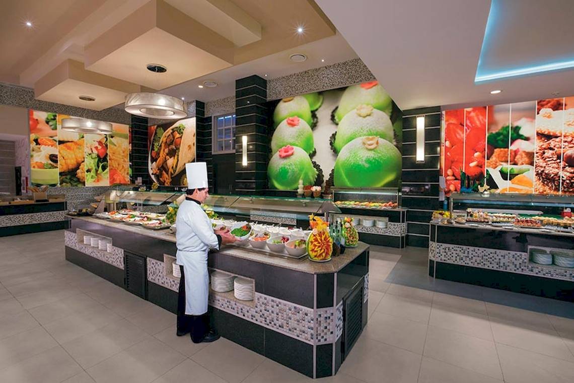 Buffet im Restaurant des Riu Palace Las Americas mit einem Koch, der Essen serviert.