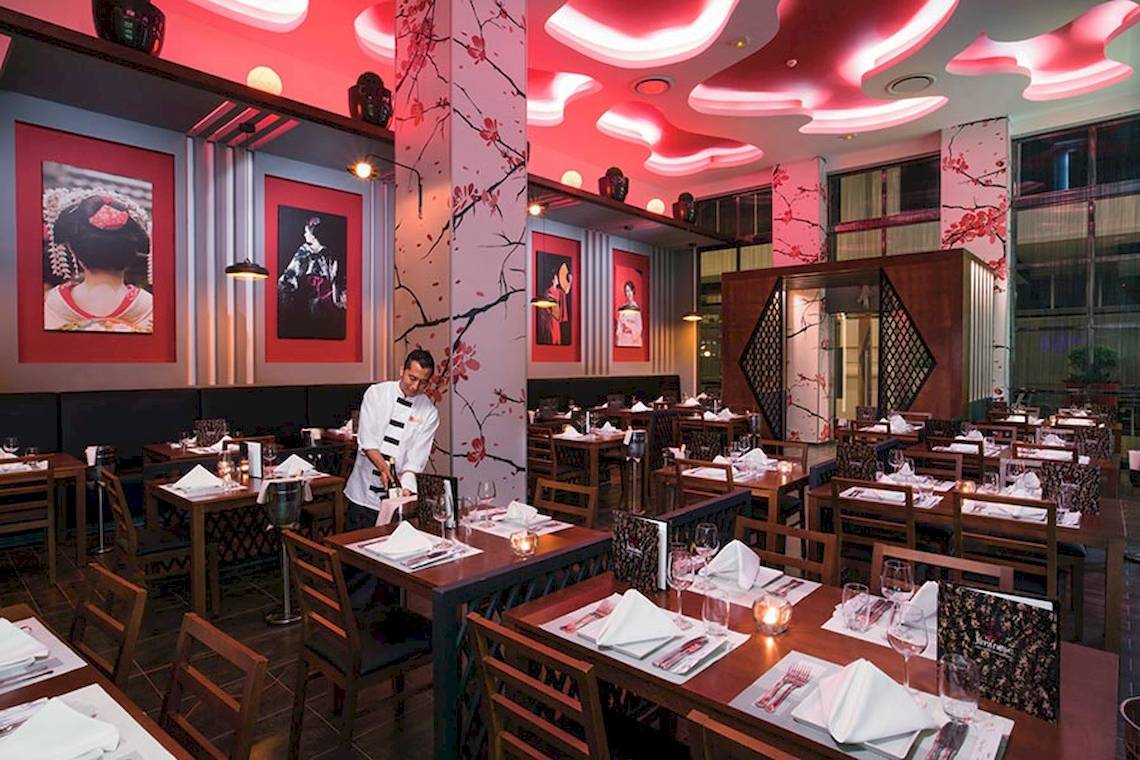 Innenansicht des Restaurants im Riu Palace Las Americas mit rotem Thema und japanischen Gemälden an den Wänden.