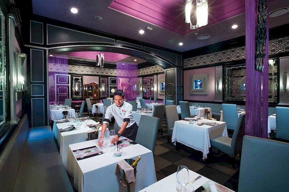 Ein Kellner bereitet Tische in einem eleganten Restaurant im Riu Palace Las Americas vor.