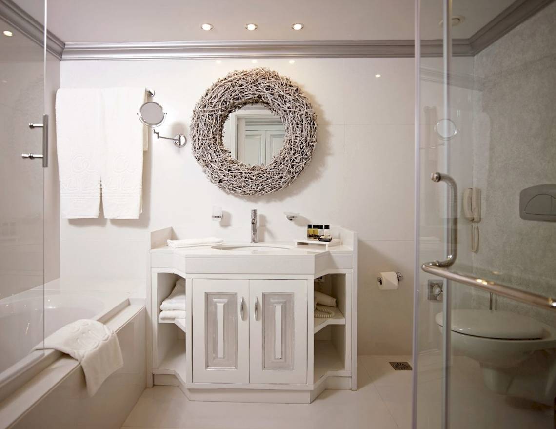 Badezimmer im Mitsis Alila Resort & Spa mit Badewanne, Waschbecken und Dusche.