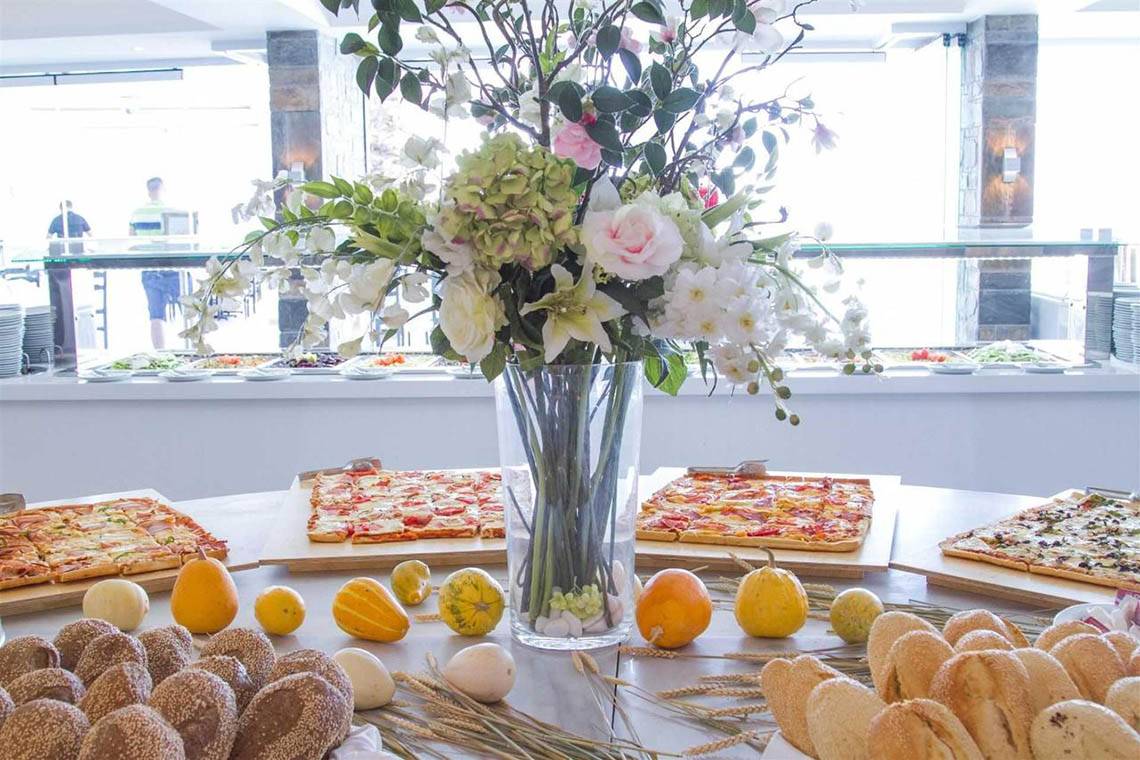 Ein Tisch im Peninsula Resort & Spa mit einer Vase voller Blumen, verschiedenen Pizzen und Brotsorten.