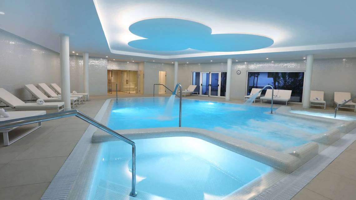 Indoor-Poolbereich des Iberostar Selection Lanzarote Park mit mehreren Liegestühlen und Wasserfällen.