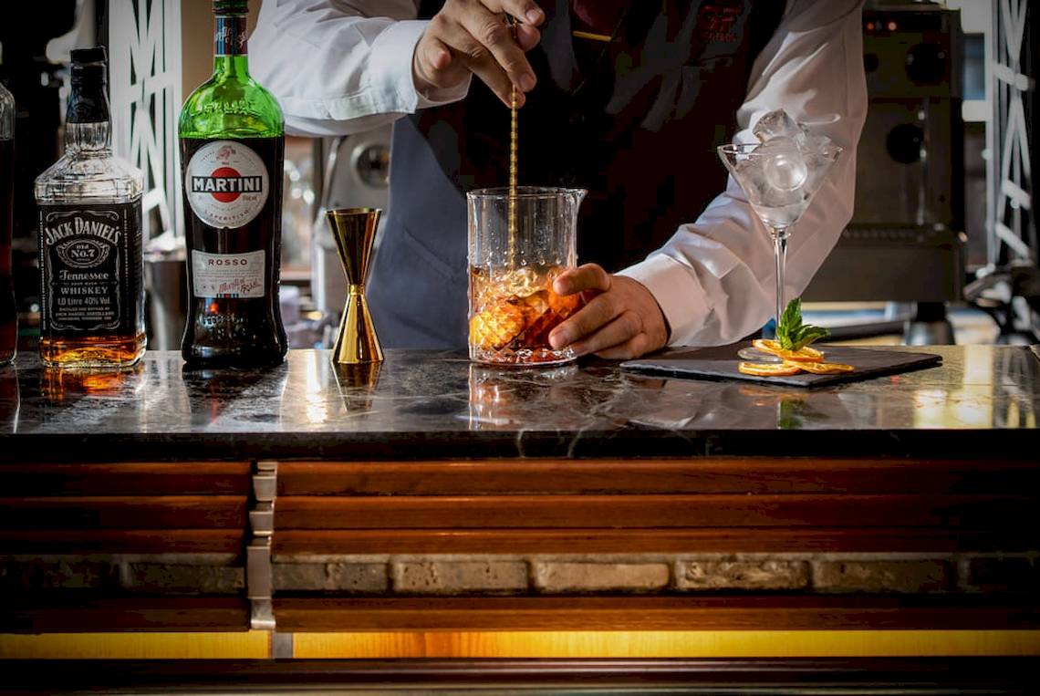 Ein Barkeeper bereitet einen Cocktail in einem Glas auf einer Bar zu.