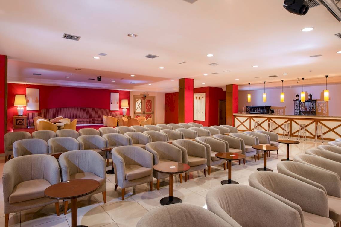 Loungebereich des GF Gran Costa Adeje Hotels mit roten Wänden und vielen Sitzgelegenheiten.