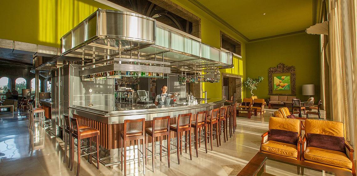 Bar im Lopesan Villa del Conde Resort mit grünen Wänden und modernem Design.