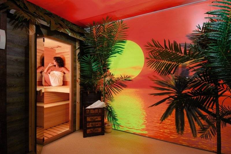 Eine Frau in einem Saunaraum des Saudade Hotels mit einer Projektion einer tropischen Nacht