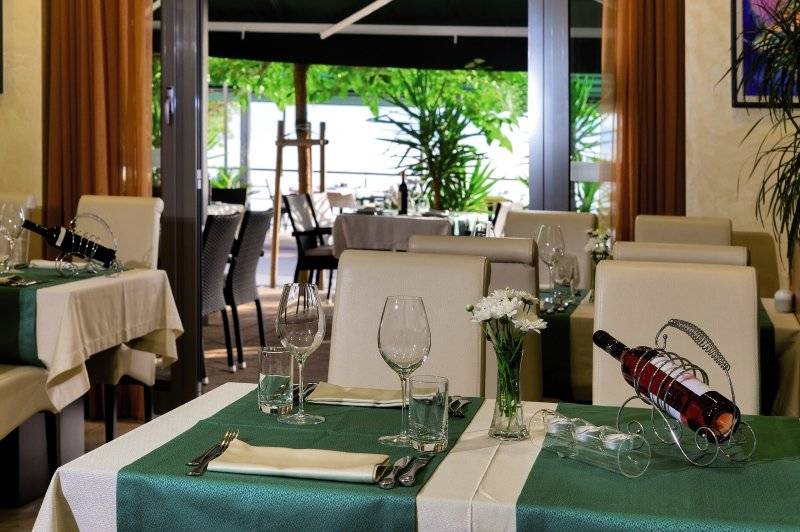 Restauranttisch des Saudade Hotels mit grünem Tischtuch und Weinflaschen.