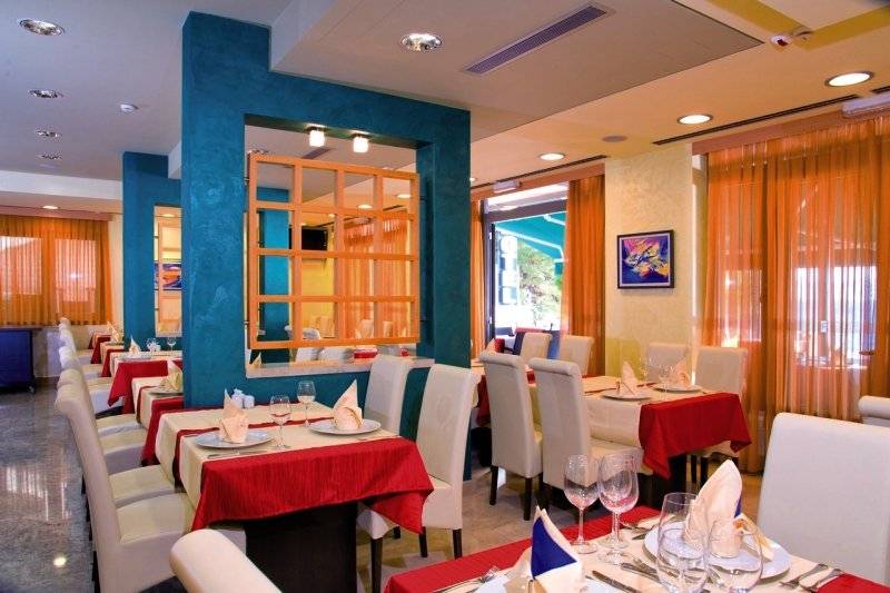 Innenansicht des Restaurants im Saudade Hotel mit blauen und gelben Wänden, weißen Stühlen und rot-weißen Tischdecken.