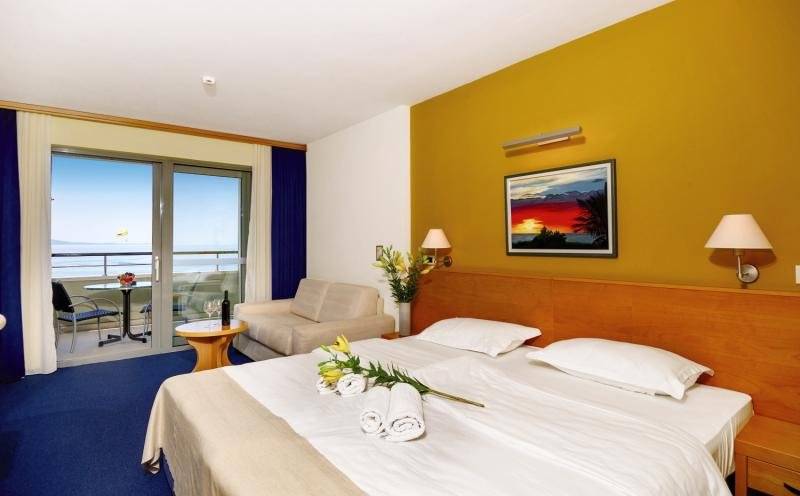 Doppelzimmer im Saudade Hotel mit Balkon und Meerblick, inklusive Bett, Couch, Tisch, und Kunstwerk.
