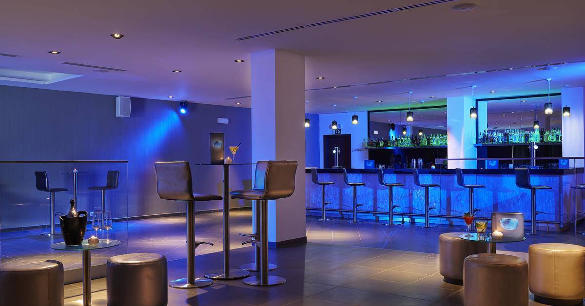 Bar im Melia Dunas Beach Resort & Spa mit blauer Beleuchtung und hochmoderner Einrichtung.