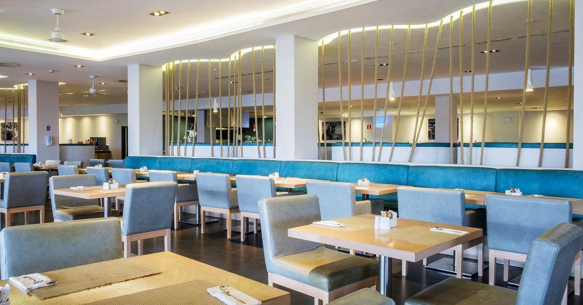 Innenansicht des Restaurants im Melia Dunas Beach Resort & Spa mit blauen Sofas und Tischen.