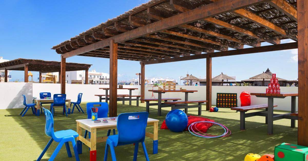 Kinderbereich auf der Dachterrasse des Melia Dunas Beach Resort & Spa mit Tischen, Stühlen und Spielzeug.