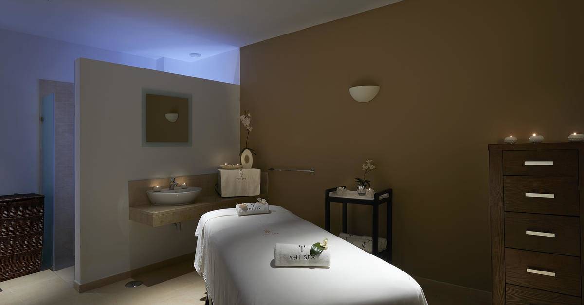 Behandlungsraum im Melia Dunas Beach Resort & Spa mit Massageliege, Waschbecken und Dekor.