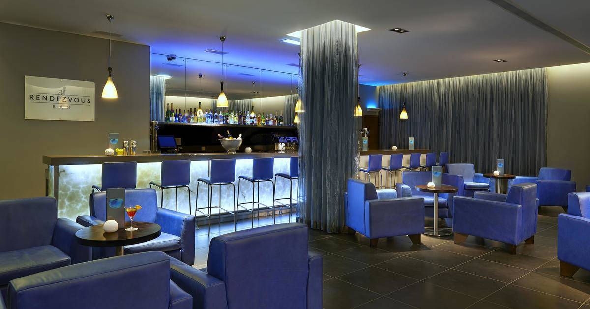 Bar und Loungebereich des Melia Dunas Beach Resort & Spa mit blauen Stühlen und Theke